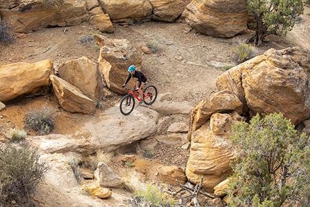 骑山地自行车的人骑在有巨石的山坡上