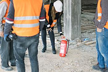 Commercial 建设 Safety Specialist explaining how to use fire extinguisher at construction site.
